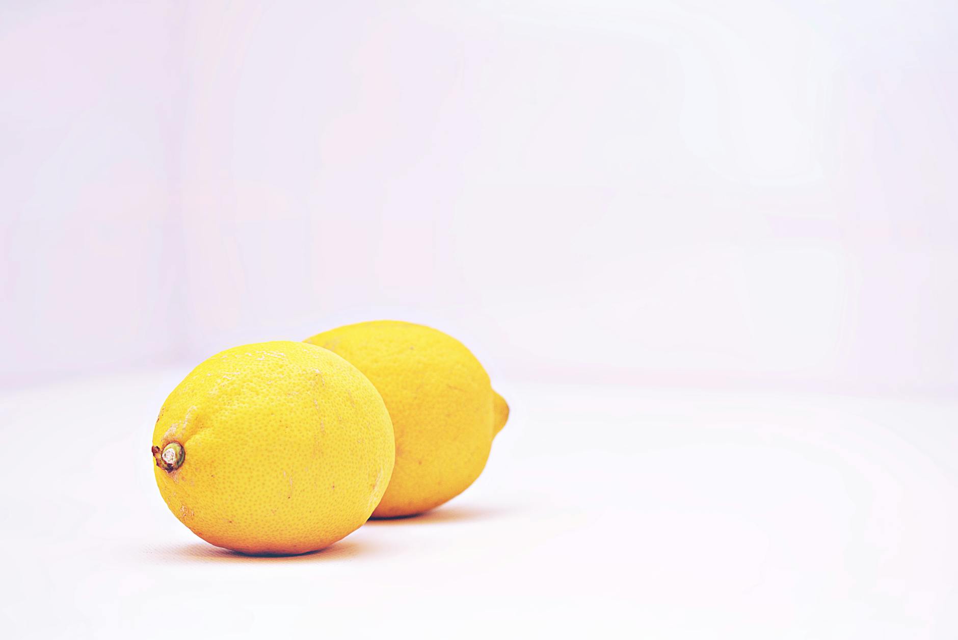 Deux citrons vibrants sur fond blanc épuré symbolisant la fraîcheur et la récupération
