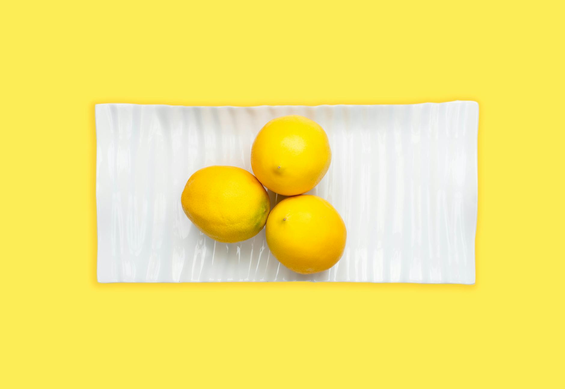 Citrons vibrants disposés sur un fond vert pastel, évoquant la fraîcheur et la sensation.