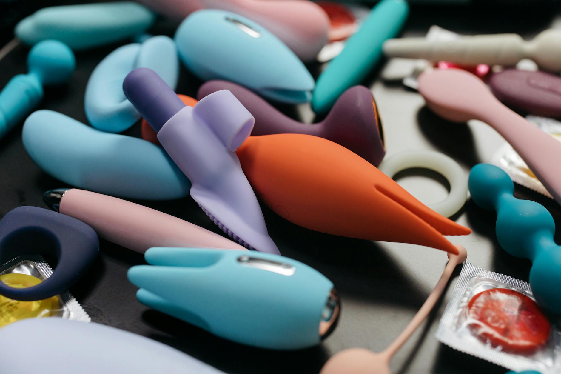 Une main tenant un vibromasseur orange contre un fond violet minimaliste
