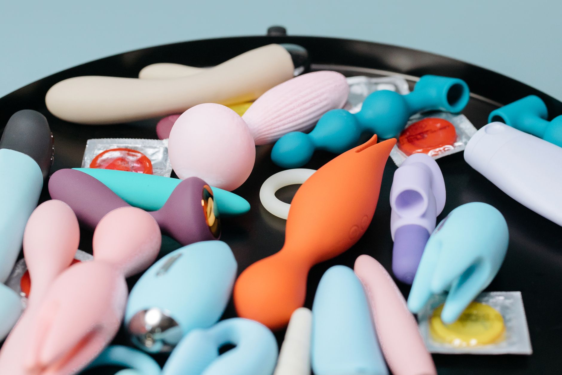 Une collection dynamique de divers jouets pour adultes sur un plateau noir, mettant en avant des formes et des couleurs diverses.