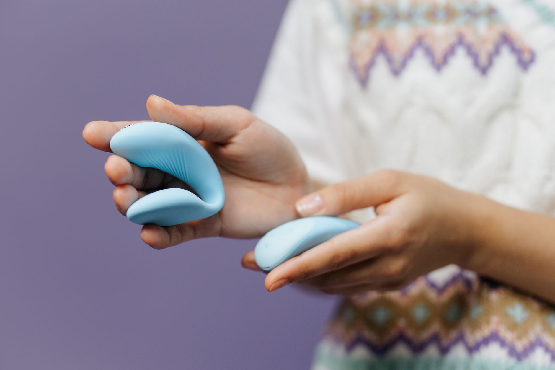 Gros plan de mains tenant un vibromasseur citron bleu élégant sur fond violet