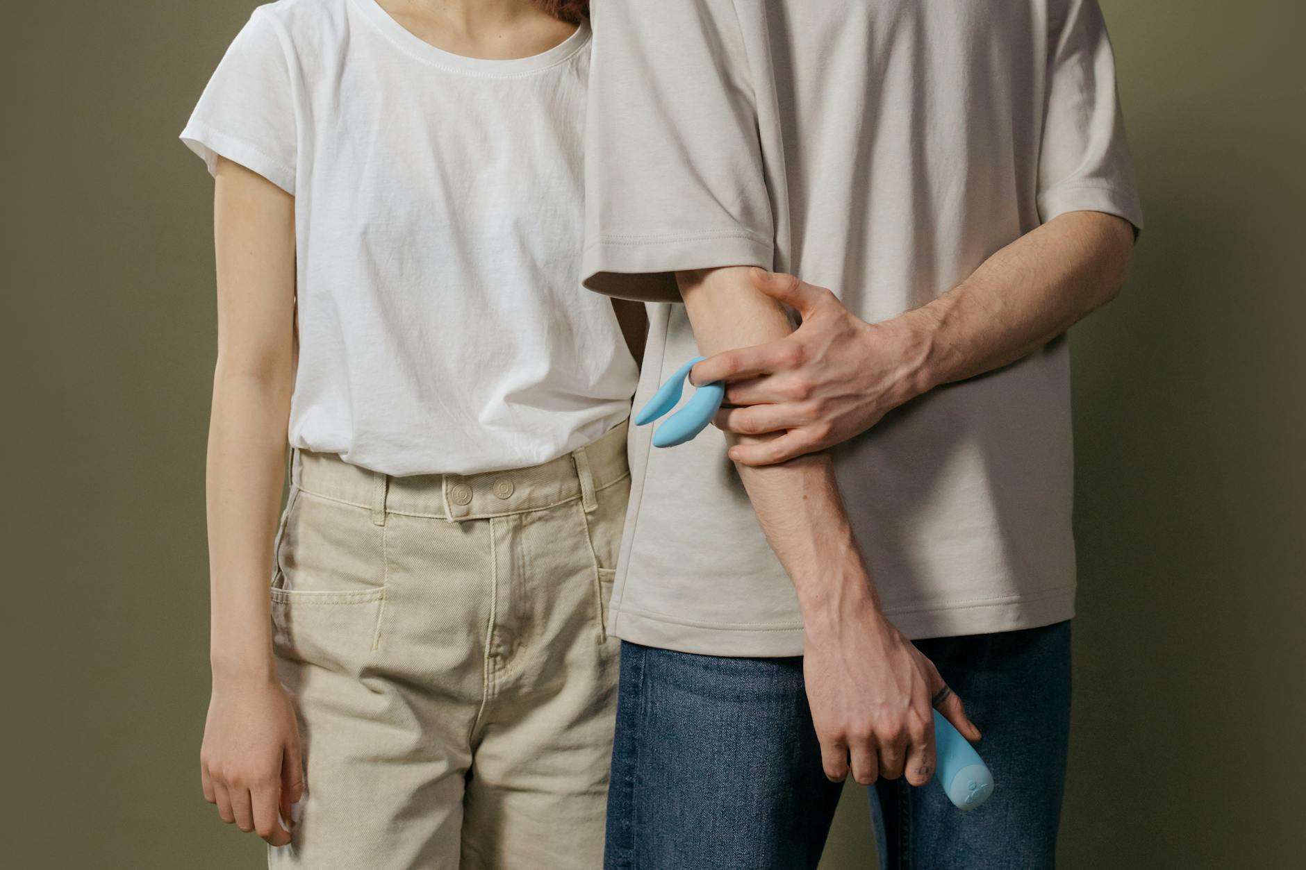 Gros plan d'une main tenant un vibromasseur orange contre un fond violet minimaliste