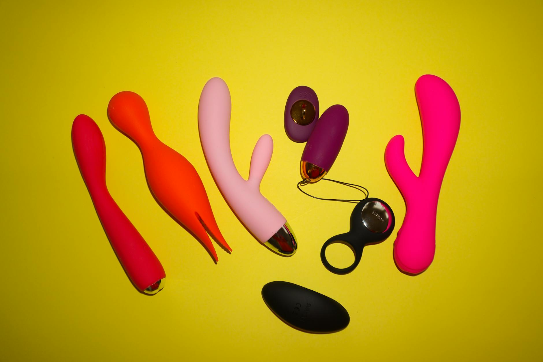 Une jeune femme tenant deux vibromasseurs colorés devant un fond violet
